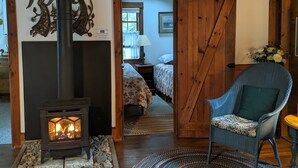 A rustic interior with a wood-burning stove, a woven rug, and a blue chair.