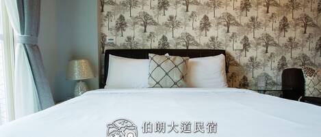 Une chambre d’hôtel avec un lit, une table de chevet, une lampe et un mur orné d’un motif représentant un arbre.