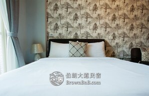 Habitación de hotel con cama, mesita de noche, lámpara y pared decorada con un diseño de árbol.