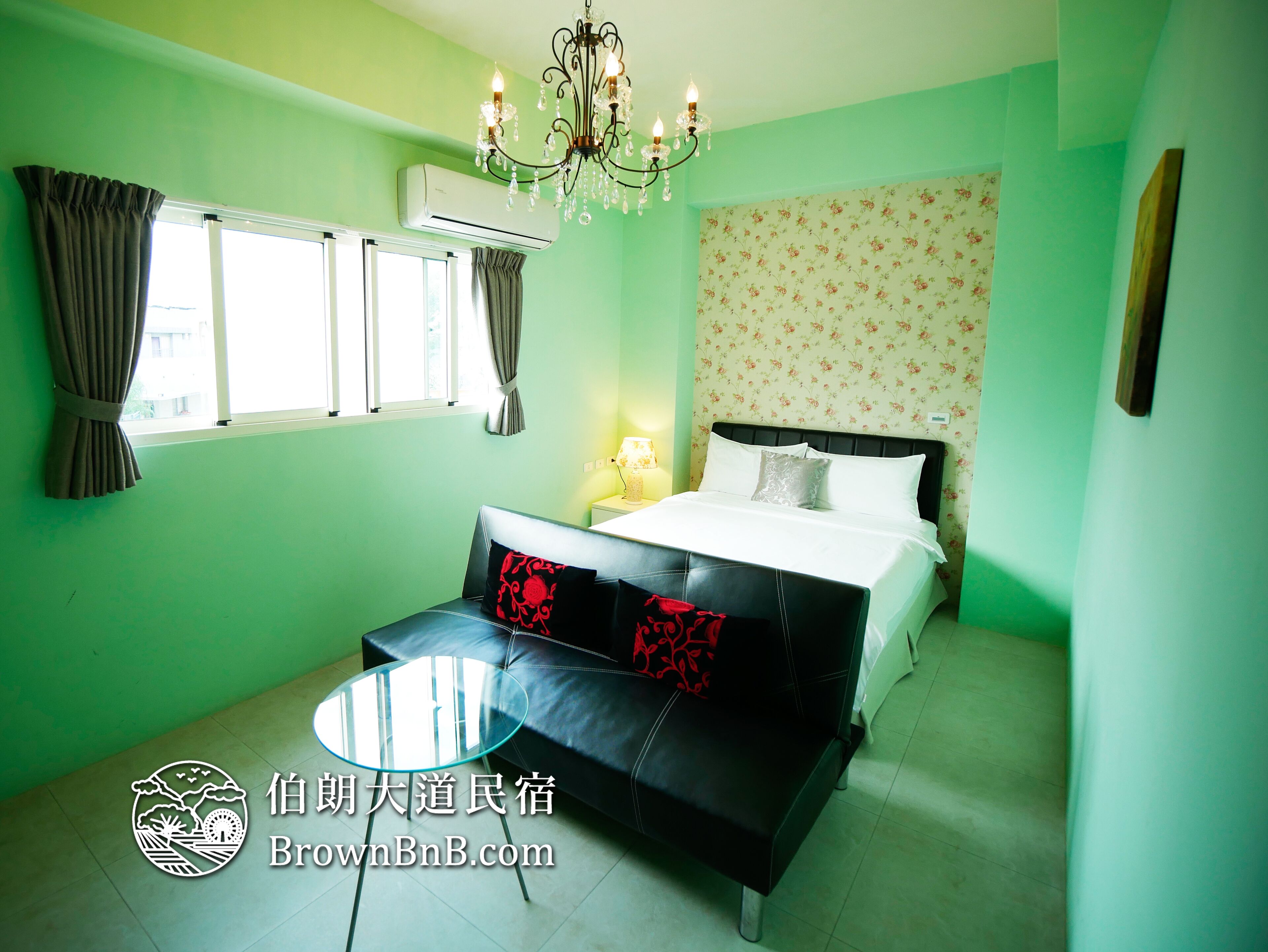 A bedroom with a bed, a sofa, a chandelier, and a window with curtains.