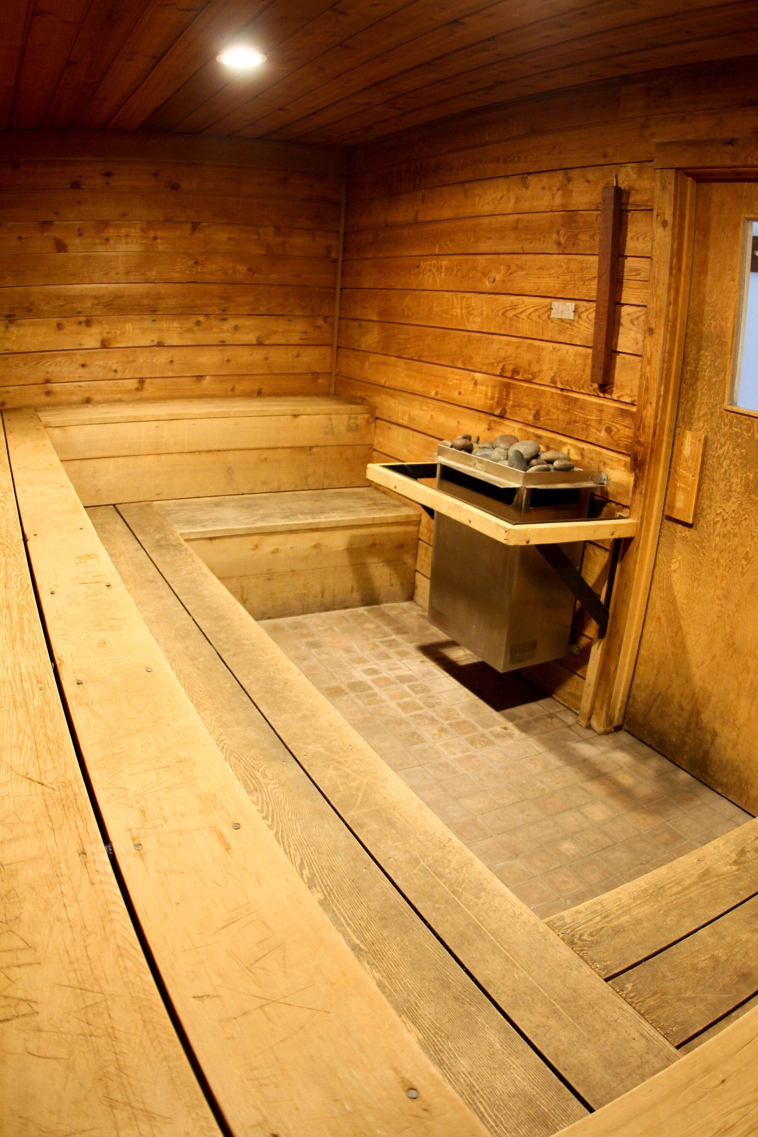 A wooden sauna with benches and a stone heating element.