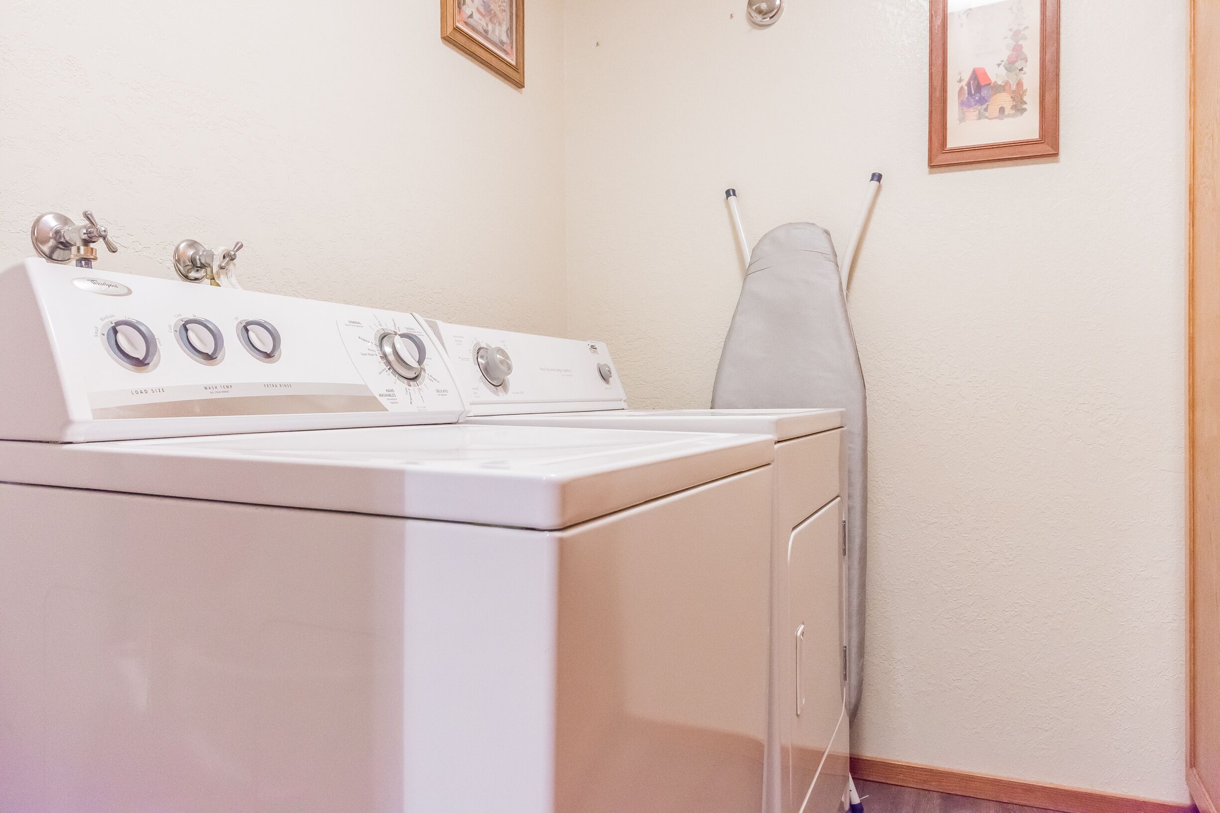 A laundry area with a white washer and dryer, a clothesline, and a framed picture on the wall.