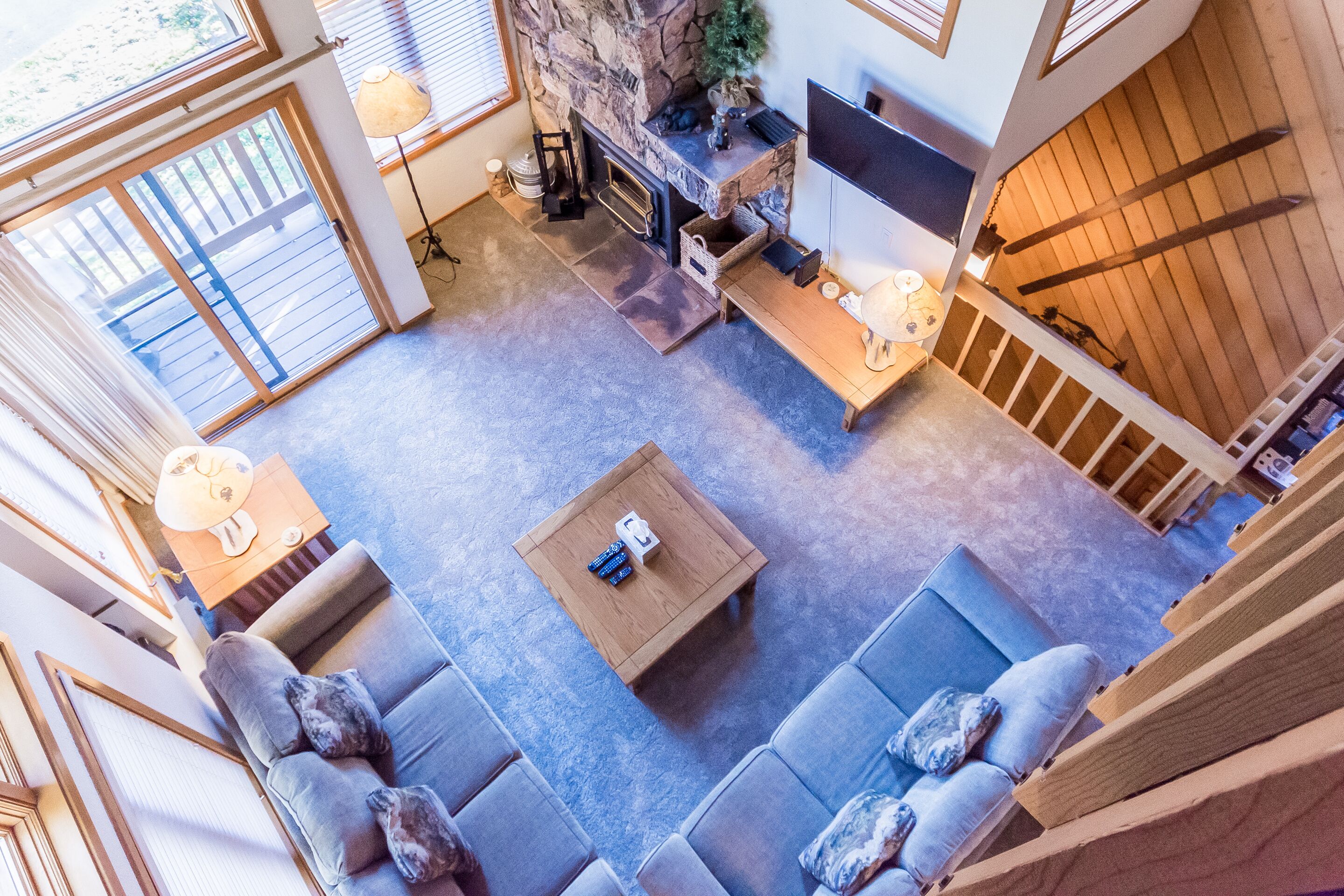 A spacious living room with a fireplace, a large TV, and a balcony.