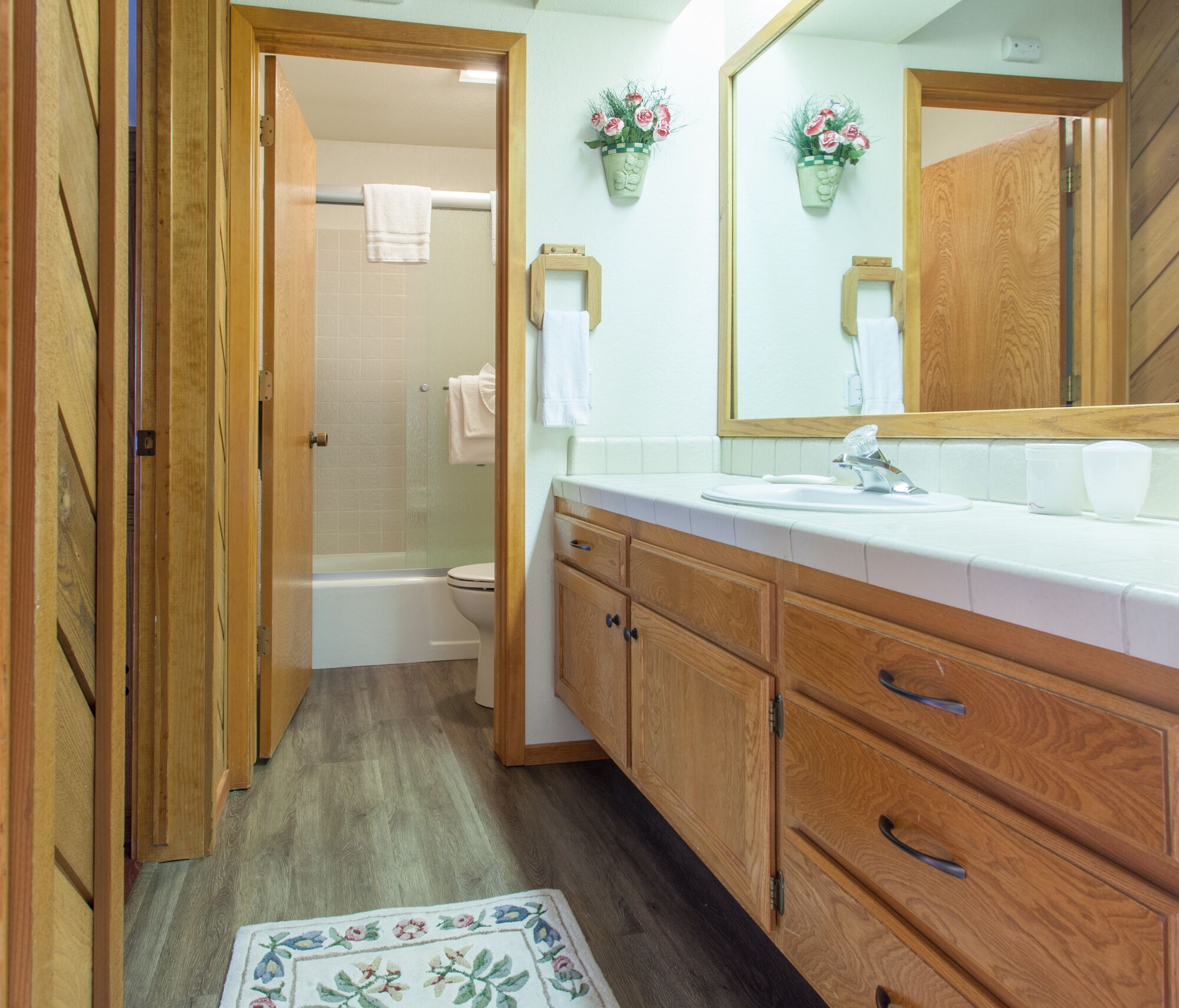 A bathroom with wooden cabinets, a white sink, and a shower area.