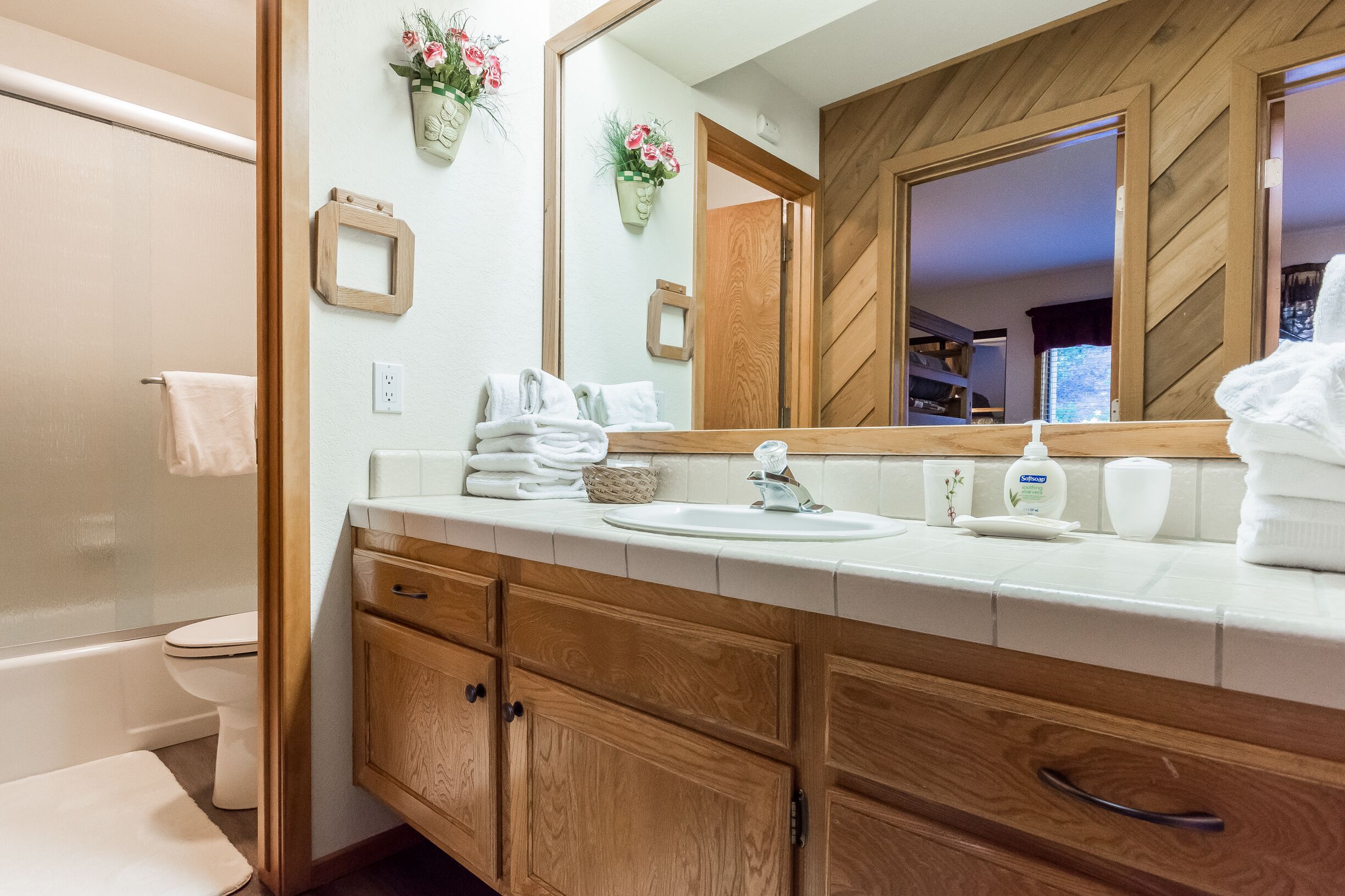 A bathroom with a wooden vanity, a sink, a mirror, and a toilet.