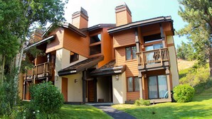 Ein modernes, zweistöckiges Haus mit überdachter Veranda, Eingangsbereich und gepflegtem Rasen.