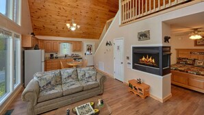 A cozy living room with a fireplace, wooden ceiling, and a sofa with animal prints.