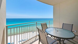 A balcony with a glass table and chairs, overlooking a beach with clear turquoise water and a distant horizon. - Stunning 11th Floor Gulf-View Retreat at Aqua Resort Free Beach Chairs (Panama City Beach)