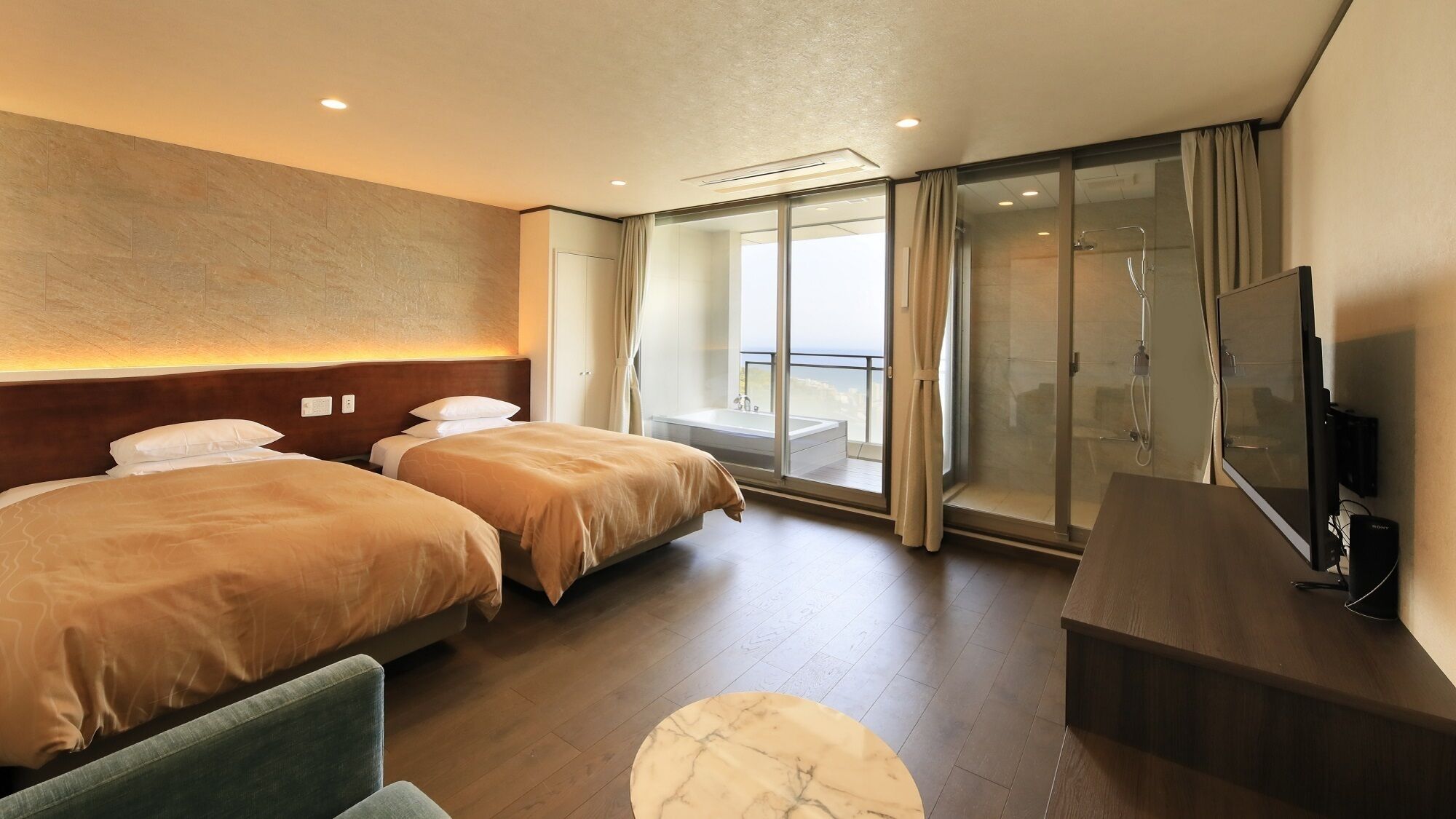 Een hotelkamer met twee bedden, een televisie, een bureau en een balkon met een glazen deur.