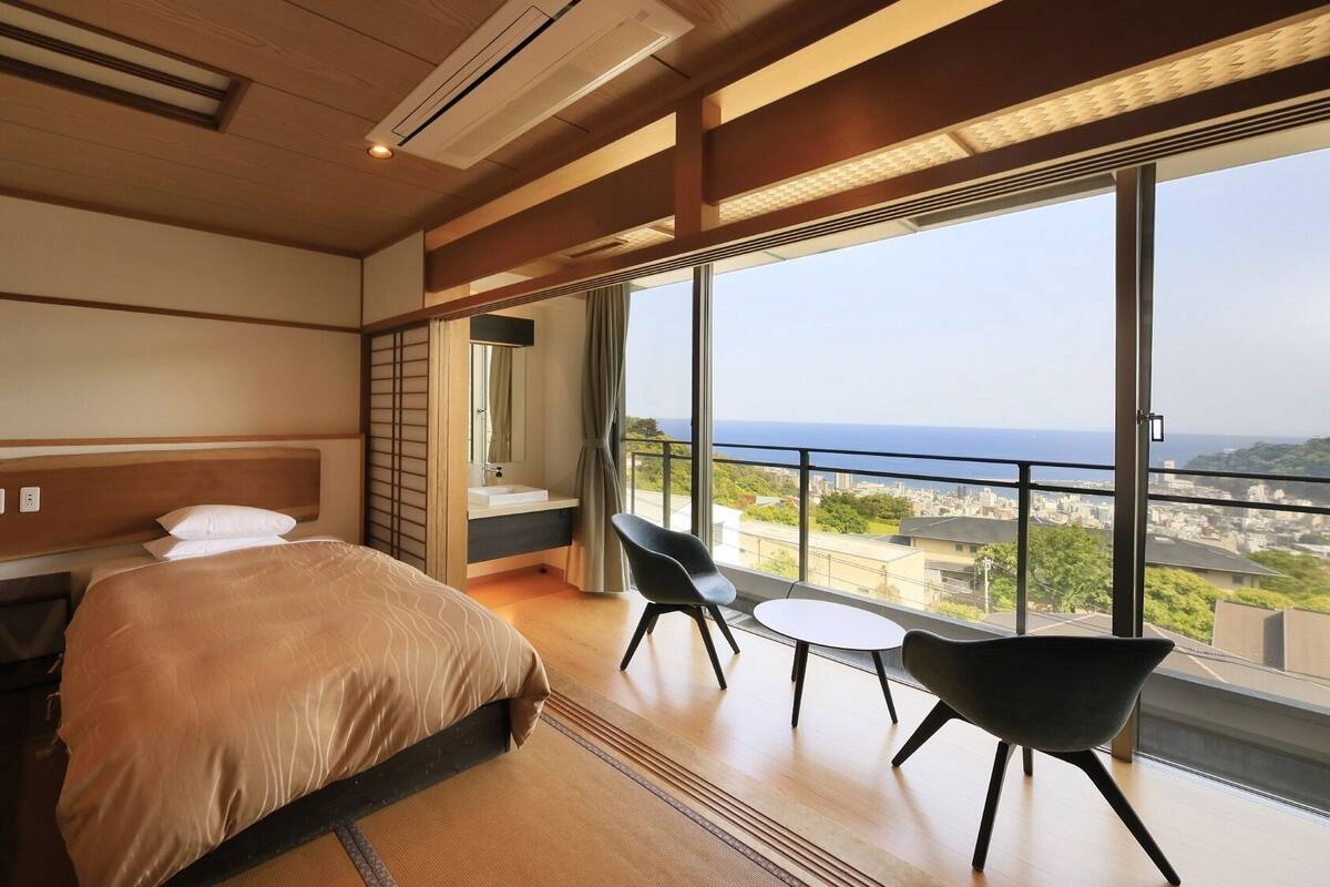 A hotel room with two beds, a balcony with a view, and a small table with chairs.