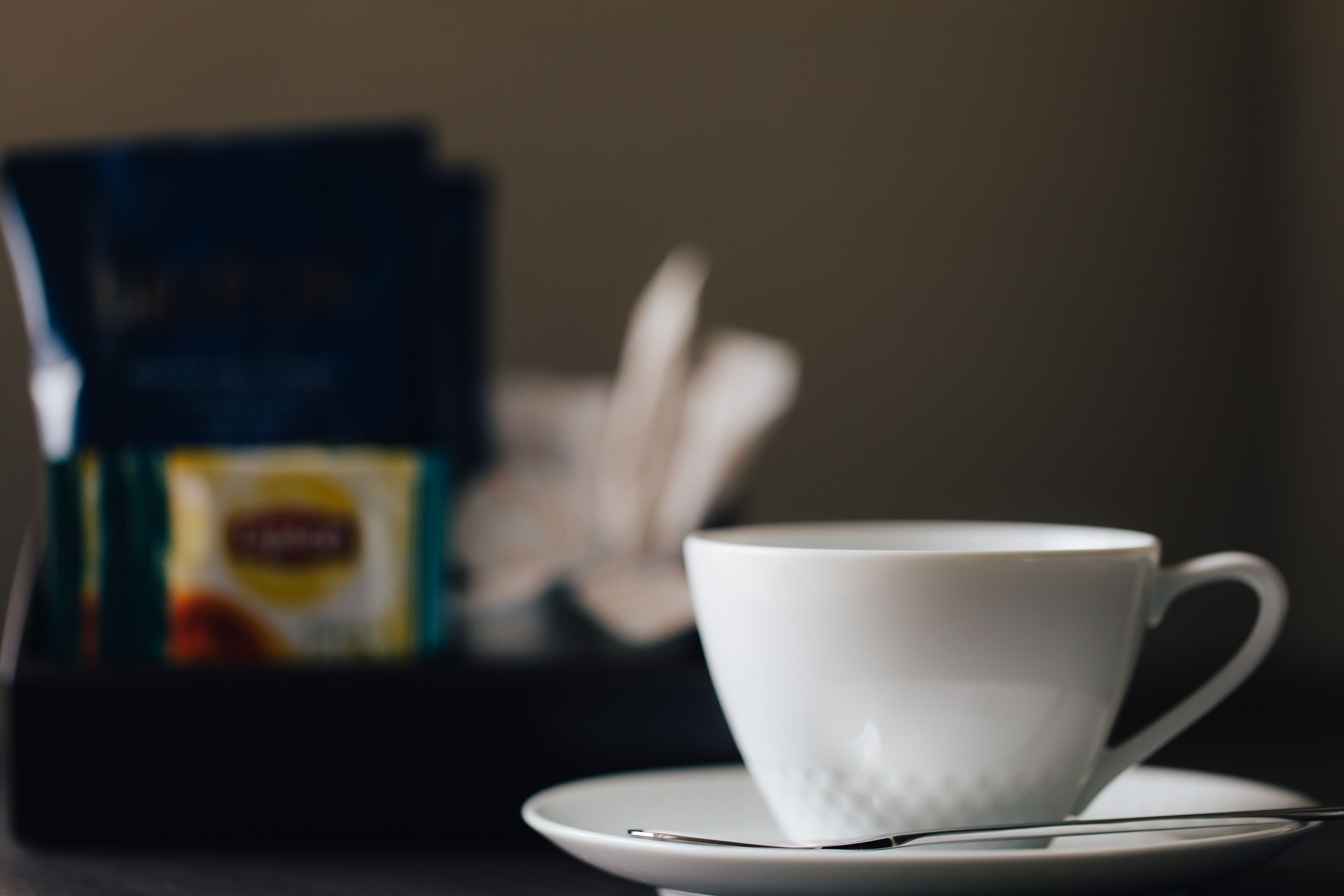 Una taza blanca sobre un platito con un fondo desenfocado.
