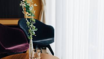 A wooden table with a clear glass vase containing a plant and a candle.