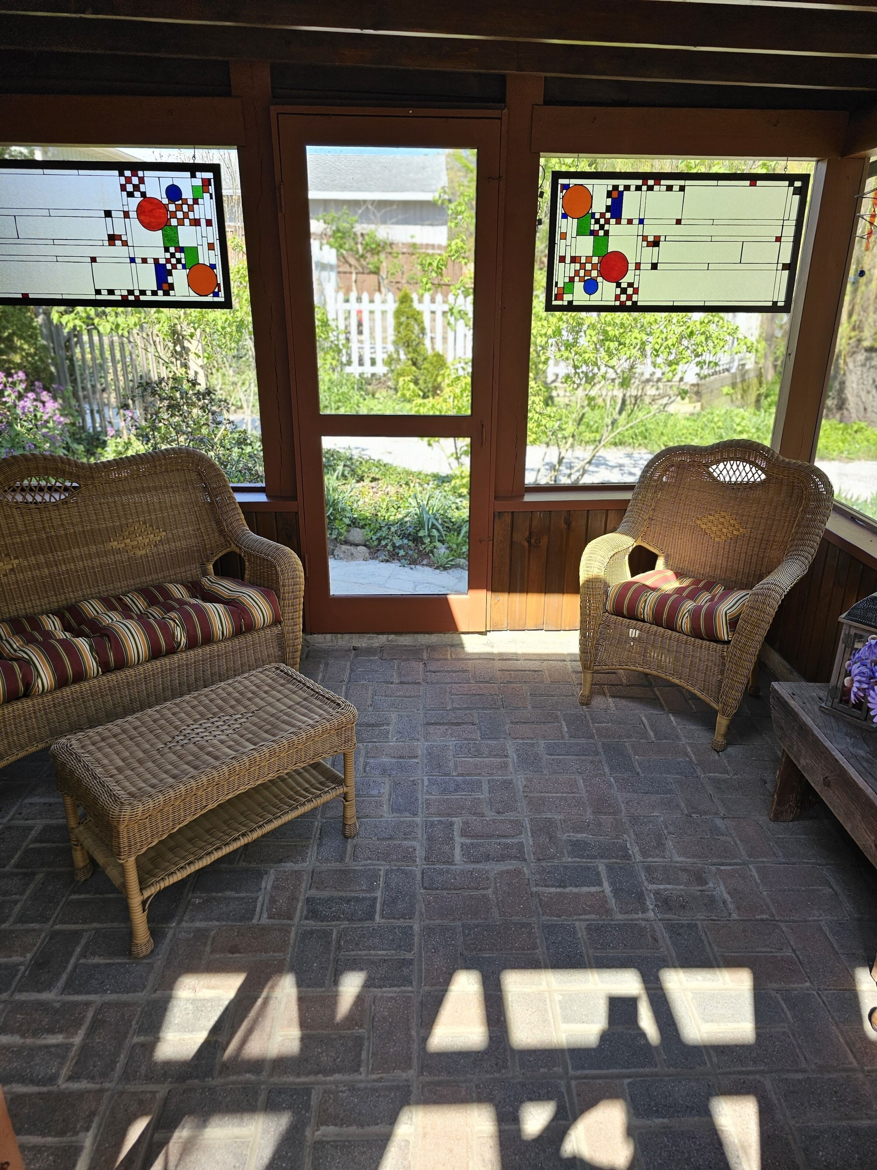 A covered patio area with wicker furniture, including a sofa and a chair, and a small table.