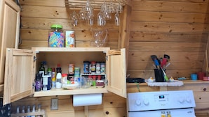 A kitchen with wooden cabinets, a stove, and various kitchen utensils and appliances.