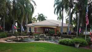 A hotel with a tiled roof, a covered entrance, and a landscaped garden with a pond. - Gem of Lake Marion! Beautiful 3 Bedroom with King Beds, HD & Internet (Kissimmee)