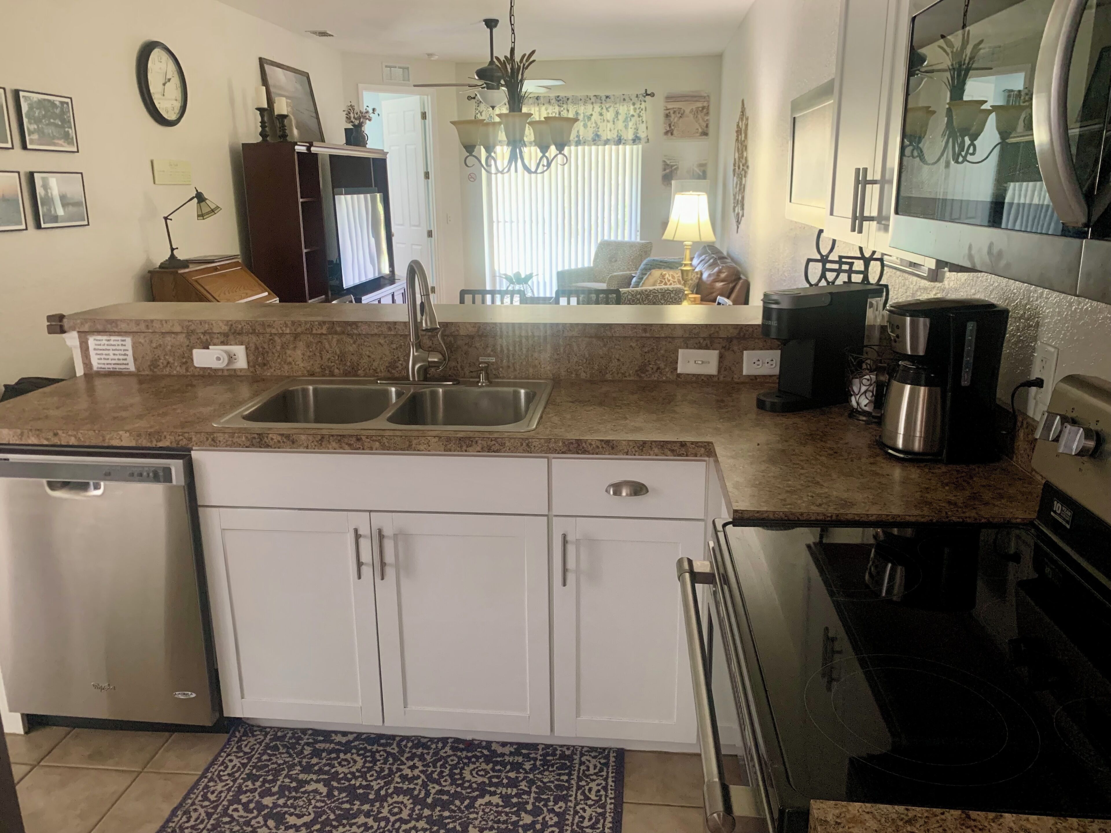 A kitchen with a dishwasher, double sink, and a coffee maker.