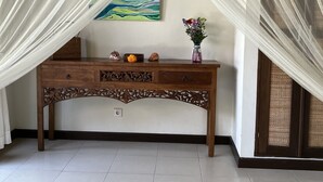 A room with a wooden console table, a painting on the wall, and a decorative vase with flowers. - Beautiful, Peaceful Villa/Excellent Location/Wonderful Balinese Staff (Penestanan, Ubud)