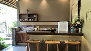A kitchen with a marble countertop, wooden stools, a refrigerator, and a shelf with kitchenware. - Beautiful, Peaceful Villa/Excellent Location/Wonderful Balinese Staff (Penestanan, Ubud)