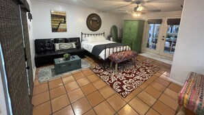 A bedroom with a bed, a green wardrobe, a black sofa, a patterned rug, and a ceiling fan. - Centrally Located, Private Bungalow with AC and parking space (San Diego)