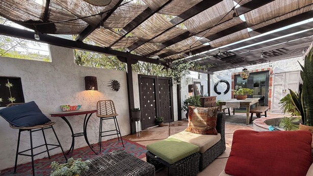 A covered patio area with wicker furniture, a cushioned bench, and a table with chairs. - Centrally Located, Private Bungalow with AC and parking space (San Diego)