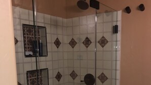 A glass-enclosed shower with a tiled wall featuring a geometric pattern. - Centrally Located, Private Bungalow with AC and parking space (San Diego)