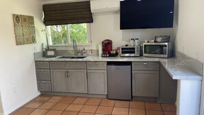 A compact kitchen with a dishwasher, a coffee maker, a microwave, and a toaster. - Centrally Located, Private Bungalow with AC and parking space (San Diego)