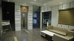 Un vestíbulo moderno con piso de mármol, una recepción, una escalera y un área de descanso con sofá y mesa de centro.