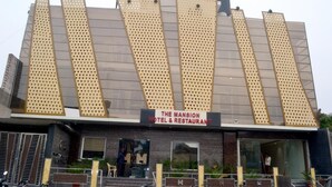 Un hotel de diseño moderno, con un letrero destacado que dice "The Mansion Hotel & Restaurant".
