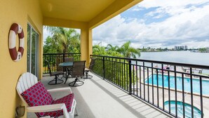 Un balcon avec vue sur la piscine, des sièges d’extérieur et une bouée de sauvetage fixée au mur.