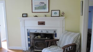 A cozy living room with a fireplace, a striped armchair, and a mantel decorated with various items.