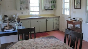 A kitchen with a dining table, chairs, and a microwave on a small table.