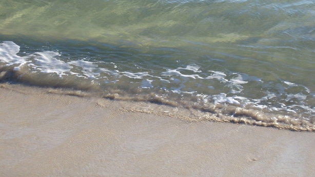 A beach with clear water and gentle waves.