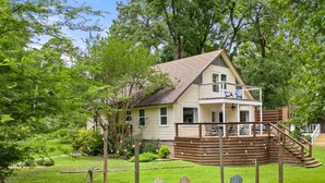 A house with a deck, outdoor seating, and a fire pit.