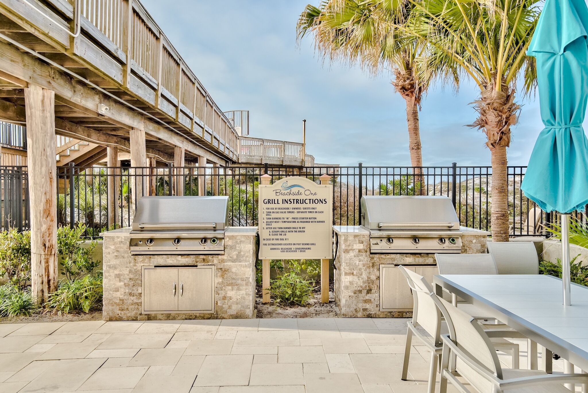 An outdoor grill area with instructions, a fire extinguisher, and a table with chairs.