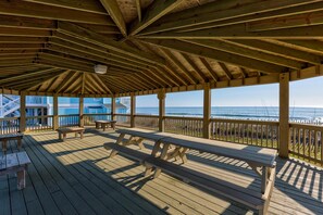 Eine Holzterrasse mit Bänken und Tischen, mit Blick auf Strand und Meer.