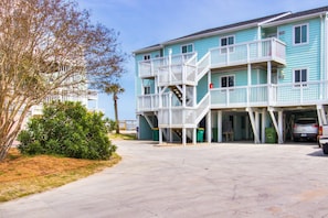 Ein zweistöckiges Gebäude mit Balkon, Garage und Parkplatz.