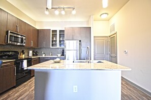 A modern kitchen with dark wood cabinets, stainless steel appliances, and a central island.
