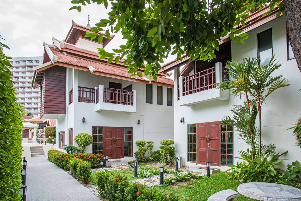 A modern residential building with a red-tiled roof, white walls, and balconies.