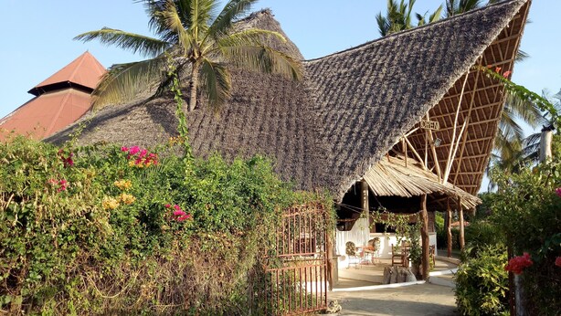 A thatched-roof structure with a garden pathway leading to a seating area. - Travellers Inn Resort Malindi (Malindi)
