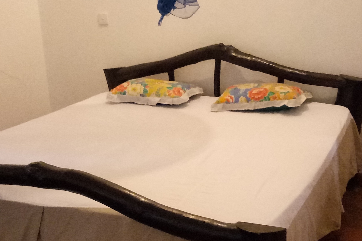 Un lit avec un drap blanc et un oreiller à motifs floraux.