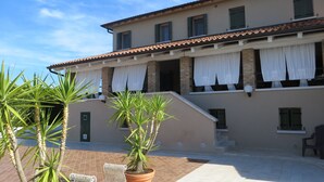 A building with a tiled roof, a covered patio area with a bench, and potted plants. - DAISY Luxury Apt in Villa, Patio, Pool, Hot Jacuzzi, A/C, WiFi, Gym, Sauna (SAN PIETRO DI CAVARZERE VENEZIA)