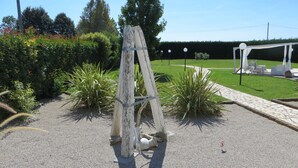 A garden with a wooden ladder, a paved walkway, and a seating area with umbrellas. - DAISY Luxury Apt in Villa, Patio, Pool, Hot Jacuzzi, A/C, WiFi, Gym, Sauna (SAN PIETRO DI CAVARZERE VENEZIA)