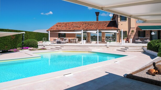 Une maison moderne dotée d’une piscine, d’un espace salon extérieur et d’un patio couvert.