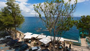 A seaside café with outdoor seating, a parking area, and a view of the sea. - Charming OLD TOWN Penthouse W Large Private Sea Balcony  (Funchal)