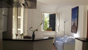 Een keuken met een fornuis, een spoelbak en een raam met uitzicht op groen.