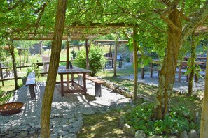Een buitenplaats met een tuin, houten pergola's, tafels en banken.
