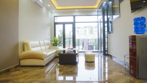 Una sala de estar moderna con un sofá de cuero blanco, una mesa de centro y un puerta de vidrio que da a un área exterior.