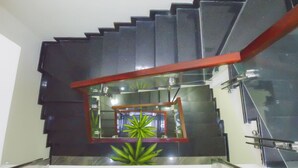 Una escalera moderna con barandilla de cristal y pasamanos rojo.
