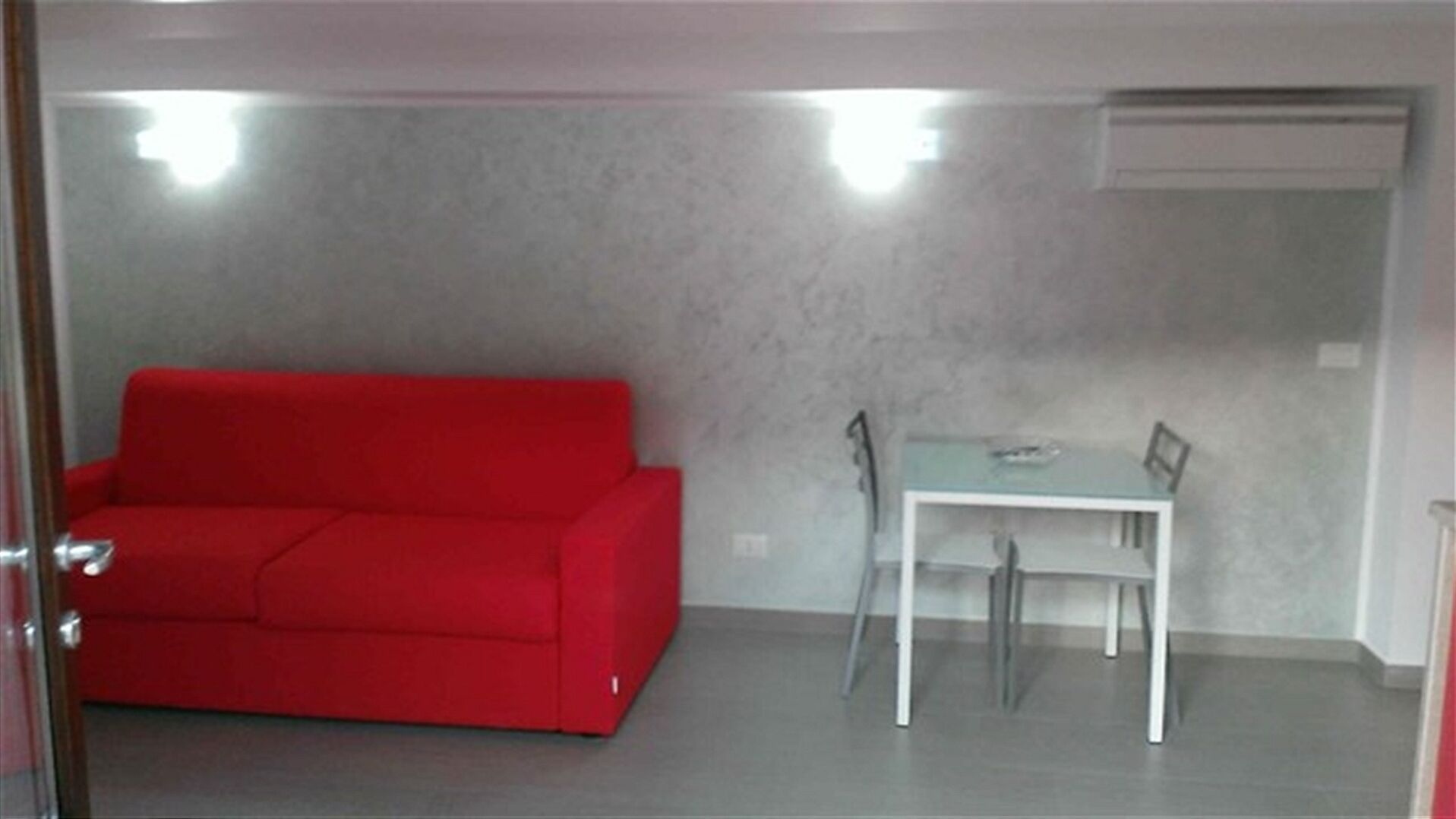 Une petite pièce moderne avec un canapé rouge et une table blanche.