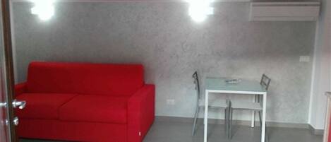 Une petite pièce moderne avec un canapé rouge et une table blanche.